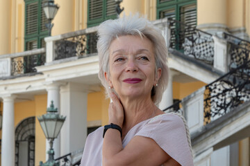 Portrait of a happy elderly gray-haired woman 65-70 years old against a background of European old architecture.