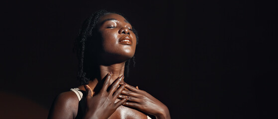 Face, hands and skincare with a natural black woman on a dark background in studio for feminine...