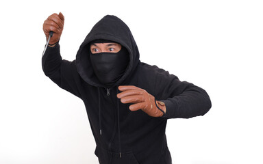 A man wearing a black hoodie, balaclava and gloves raised a knife; threatening expression