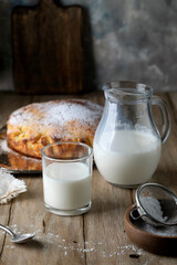 Homemade pie and milk poured into a glass glass on a rustic table