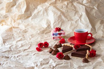 Obraz na płótnie Canvas バレンタイン・イメージ　贈り物と深紅のバラと自家製チョコレート・タルトとチョコレート菓子（しわくちゃのクラフト紙の背景）