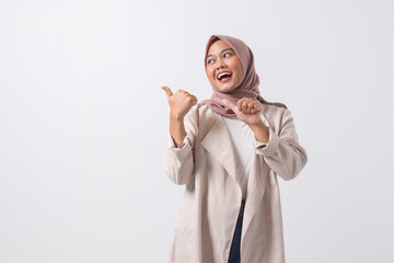 Portrait of attractive Asian hijab woman in casual suit making thumb up hand gesture, saying good...