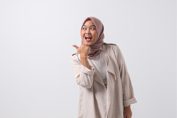 Portrait of attractive Asian hijab woman in casual suit making thumb up hand gesture, saying good...