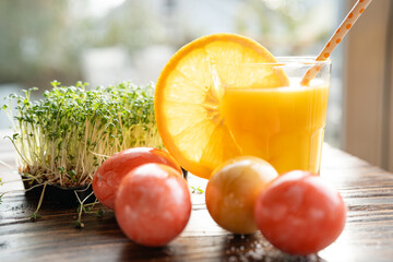 Healthy orange juice with easter eggs and fresh cress on wooden table. Close-up with short depth of...