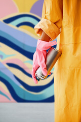 Cropped image of street artist with spray paint can in hand near colorful graffiti wall