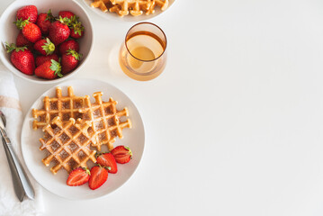Belgian waffles with strawberry and powdered sugar on white plate. Breakfast food concept. Copy...