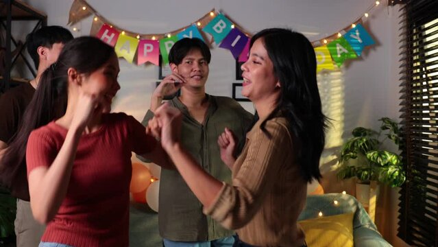 Group of young women celebrating their friend forthcoming marriage, young asian female happy smiling and dancing with friends in birthday party at home