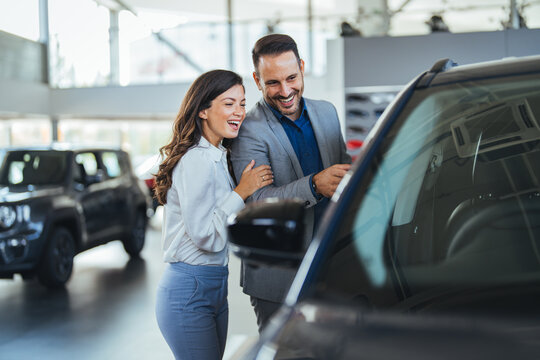Cute couple peering into a car at a dealer while deciding whether to buy. Spouses Looking At Car Interior Buying Vehicle In Store. We should organise a test drive