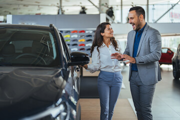 Shot of a young couple looking at cars at a car dealership. I think we can both agree that this is the car for us. Visit to the dealership.
