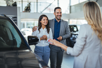 Buying Vehicle. Family Couple Choosing Car Consulting With Professional Auto Salesman In Dealership Center. Selective Focus. Couple Choosing Car