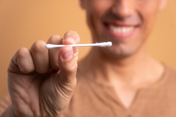 detail hands of brazilian man showing paper and cotton swab in beige background. biodegradable, hygiene concept. 