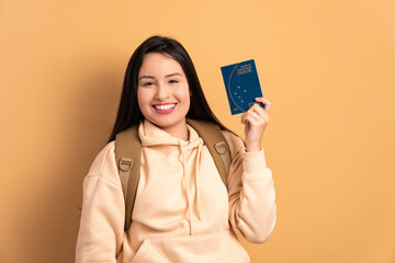 joyful young brunette woman showing brazilian passport in all beige colors. travel, trip, brazil concept.