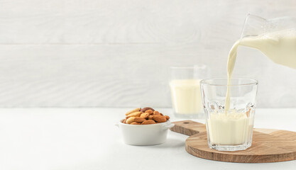 pouring nut milk into cup. lactose-free vegan drink. dairy free milk drink. Long banner format. copy space for text
