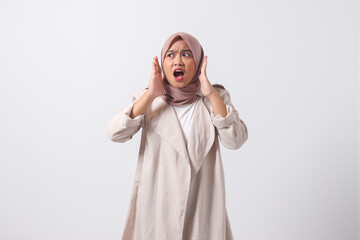 Portrait of frightened Asian hijab woman in casual suit making shocked hand gesture, showing...