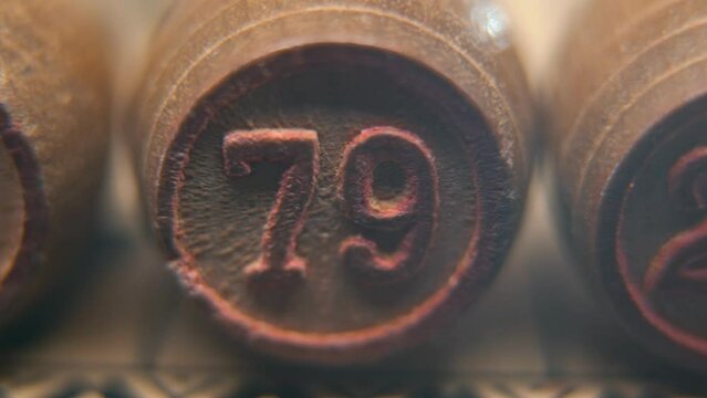 Cinematic macro smooth shot of Bingo wooden barrels in a row, woody figures, old numbers vintage board game, number 79, slow motion, commercial gimbal movement, dreamy lighting, pan right