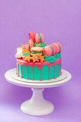 Birthday cake with turquoise frosting and pink birthday decorations ready for a birthday party, festive background. Pink donuts and macaroons