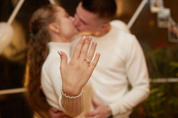 Young man and his happy fiancee showing engagement ring