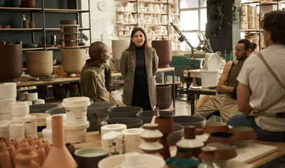 Smiling manager talking with workers in a ceramics studio