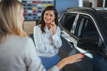 Beautiful caucasian female client customer choosing new car. Businesswoman looking for a new car,...