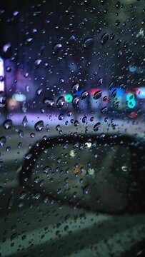 Melting snow water drops on the car window with view to the outside mirror. Winter night urban scene