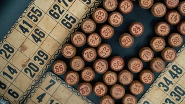 Cinematic close-up smooth shot from above of a pile of Bingo wooden barrels in a square, woody figures, old numbers background, vintage board game, slow motion 120 FPS commercial rotating gimbal video