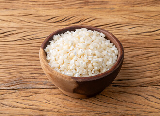 Dried canjica, hominy or white corn on a bowl over wooden table