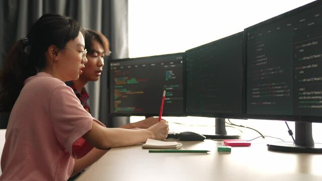 Slow motion back end software developer engineer for computer programming working together on debugging writing computing code, solving complex algorithms display on monitor in office. Burgeoning