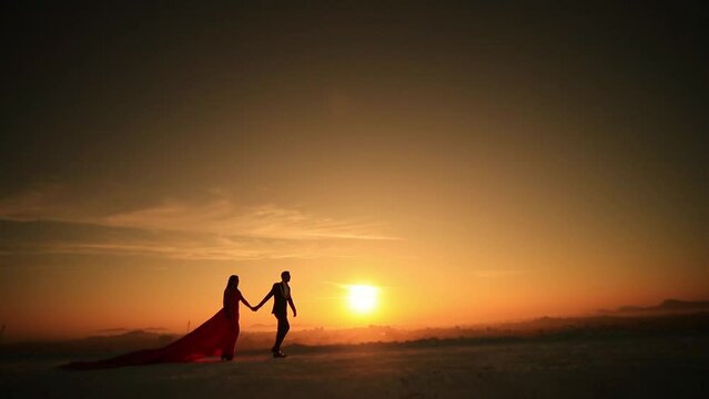 Beautiful couple walking against the sunset while holding one other's hands.