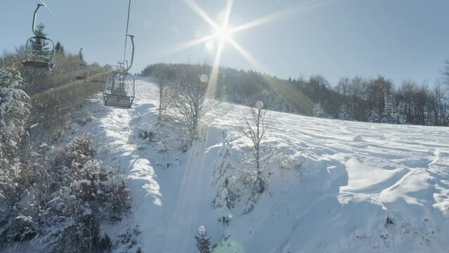 Pov riding ski lifts winter snow covered slopes sunny day sunstar