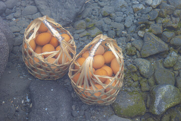 Selective focus of two bamboo baskets under clear water, Boiling chicken eggs in the natural hot...