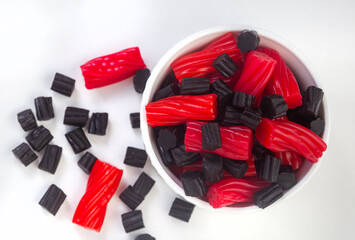 Bowl of mixed red and black licorice, top view with copy space on white