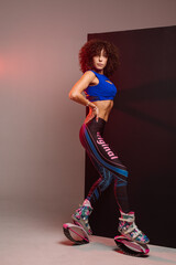 Sporty woman with curly hair in Kangoo jumpers on studio background - 718041294