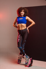 Beautiful sporty woman with curly hair in kangoo jumpers on studio background - 718041410