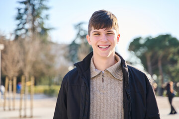 Successful student at university campus, education concept. Smiling man with perfect teeth posing outdoors.