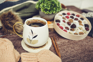 Cup of coffee with autumn leaves and knitted scarf on wooden background