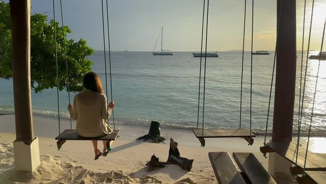 Woman calmly swinging in stunning sunny Maldives beach bar: Malahini Kuda Bandos