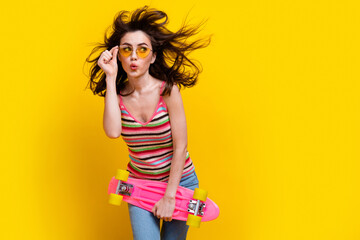 Portrait of excited girl fluttering hair touch glasses hold skateboard look at offer empty space...