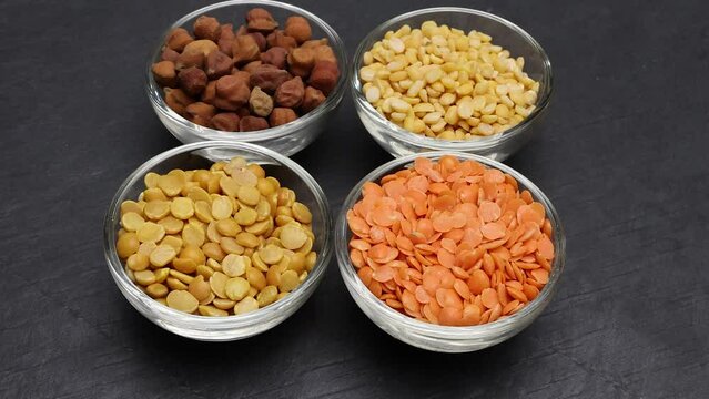 variety of lentils pulses red masoor mung dal yellow split chickpeas pigeon peas in mini glass bowl on black slate background move pan keep