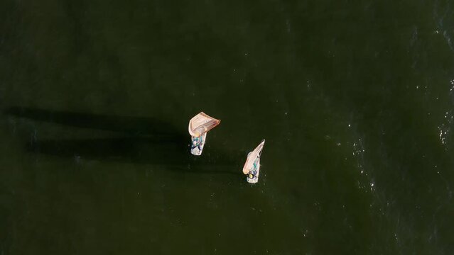 Woman and man control the sail of a windsurf board while sailing Aerial Top view