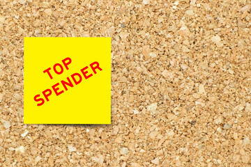 Yellow note paper with word top spender on cork board background with copy space