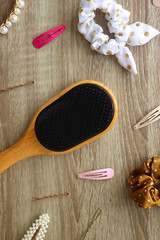 Wooden hairbrush, scissors and various headbands, hair clips and scrunchies on wooden background. Flat lay.