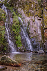 Motion of blurred water falling on schist stones with vegetation into a small lagoon in Fraga da Pena, Pardieiros - Arganil PORTUGAL