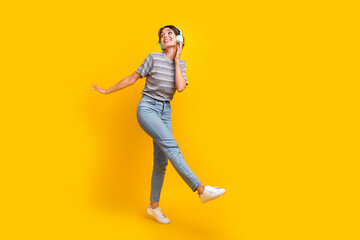 Fototapeta na wymiar Full length photo of cheerful lovely person arm touch headphones rejoice empty space isolated on yellow color background