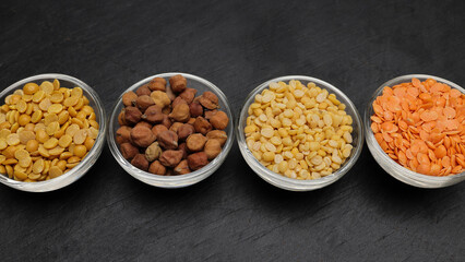 variety of lentils pulses red masoor mung dal yellow split chickpeas pigeon peas in mini glass bowl on black slate background