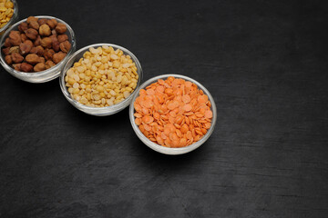 variety of lentils pulses red masoor mung dal yellow split chickpeas pigeon peas in mini glass bowl on black slate background