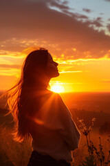 Silhouette of a woman standing in nature at sunset