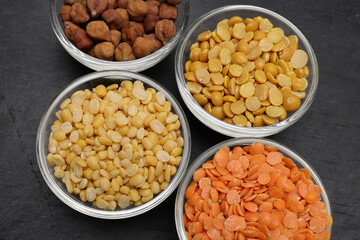 variety of lentils pulses red masoor mung dal yellow split chickpeas pigeon peas in mini glass bowl on black slate background