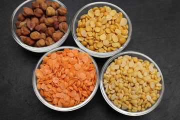 variety of lentils pulses red masoor mung dal yellow split chickpeas pigeon peas in mini glass bowl on black slate background
