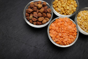 variety of lentils pulses red masoor mung dal yellow split chickpeas pigeon peas in mini glass bowl on black slate background