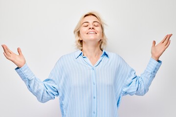 Portrait blond young woman happy face smiling joyfully with raised palms and shocked open mouth isolated on white studio background.